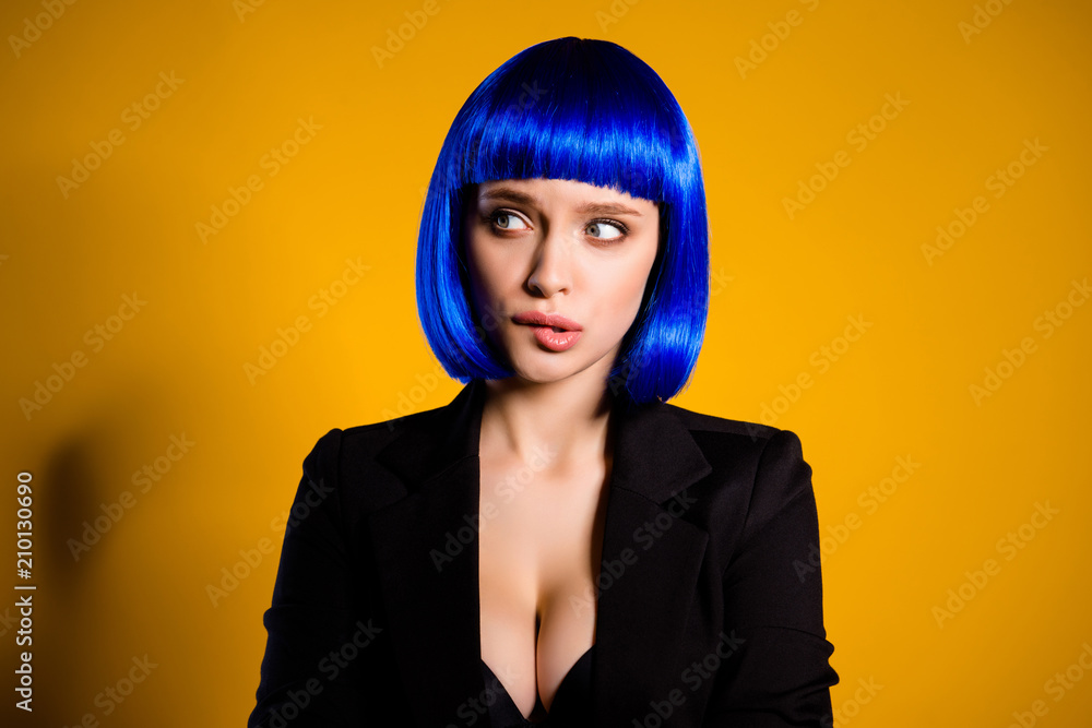 Portrait of worry confused woman in bright blue wig black jacket having sexy decollete big boobs biting low lip looking to the side isolated on yellow background Portrait of worry confused woman in bright blue wig black jacket having sexy decollete big boobs biting low lip looking to the side isolated on yellow background