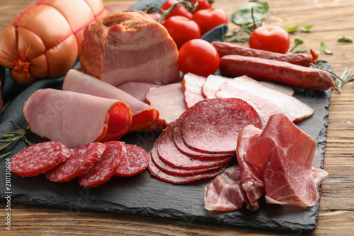 Assortment of delicious deli meats on slate plate photo