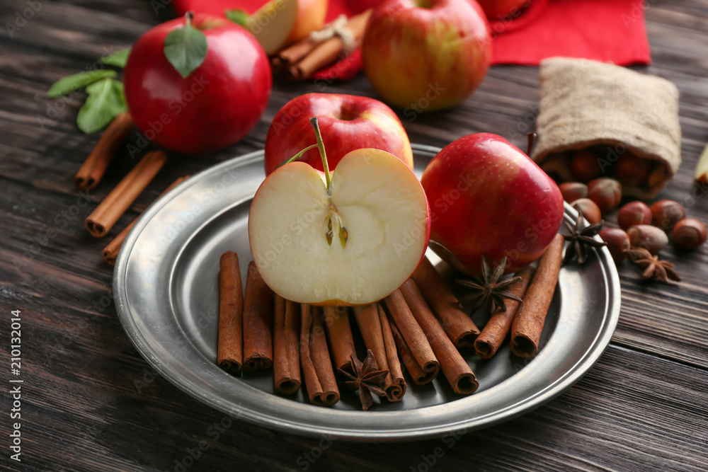 Plate with fresh apples and cinnamon on wooden table