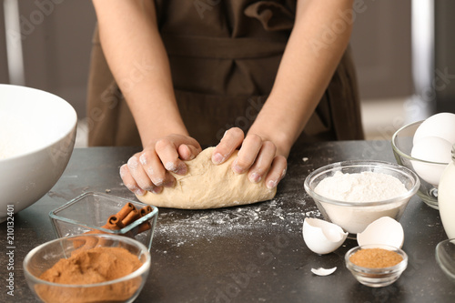 Woman kneading dough for cinnamon buns at table
