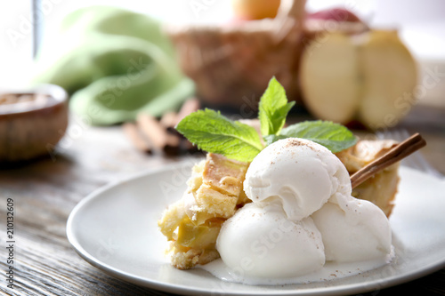 Plate with piece of delicious apple pie and ice cream on wooden table, closeup