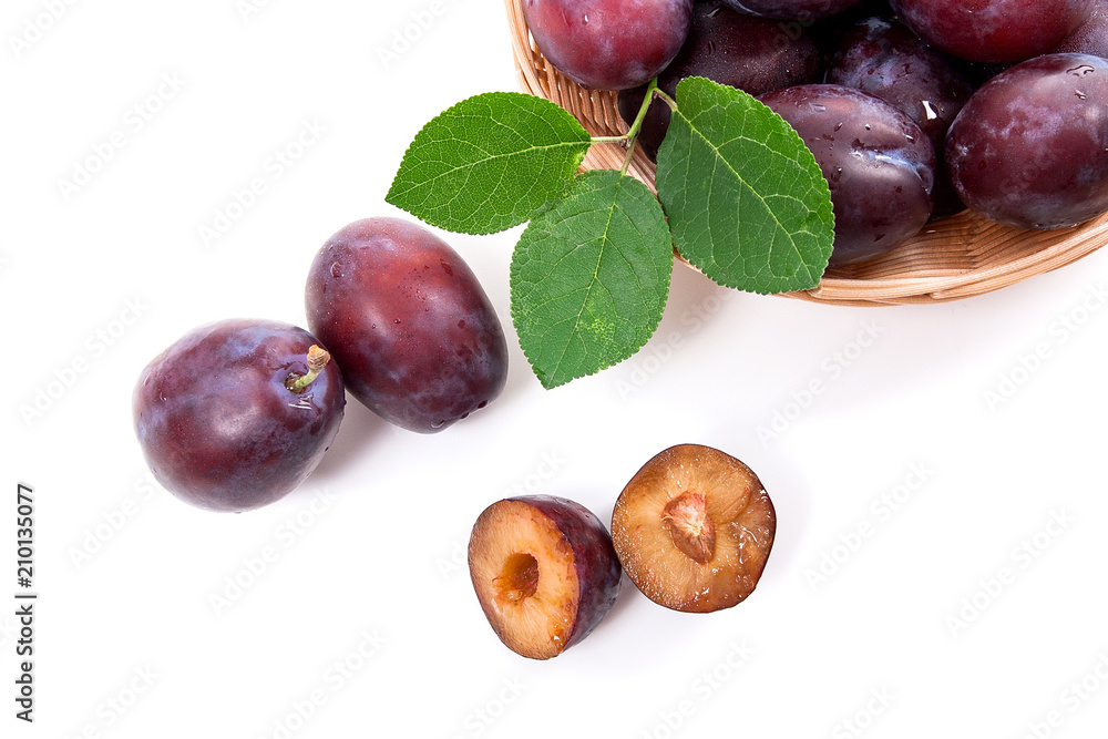 Yellow wooden basket with ripe plums, whole and half ripe plums isolated on a white background.. Yellow wooden basket with ripe plums, whole and half ripe plums isolated on a white background..
