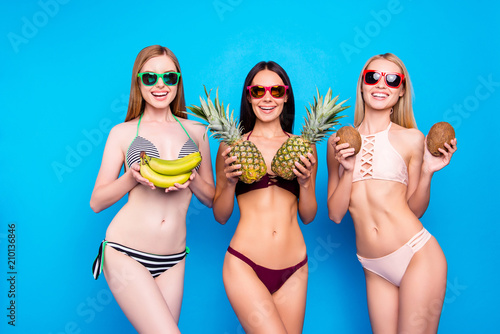 Healthy nutrition food diet fitness fit lifestyle concept. Portrait of charming cheerful sisters with slender fir figure holding fresh fruits in hands isolated on bright blue background