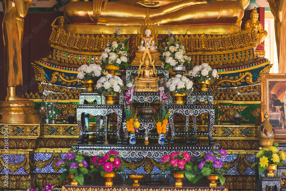 Sitting Buddha statue in Temple with flowers decoration.