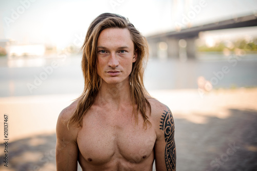 Portrait of a young handsome long-haired man on the beach