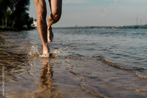 Muscular male feet running along the beautiful river bank © fesenko