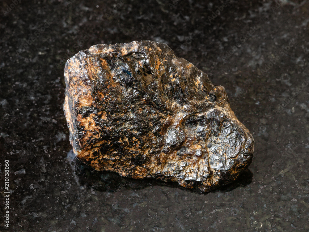 rough Cassiterite (Tin ore) stone on black