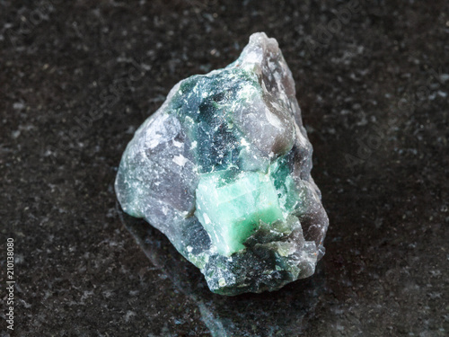 rough crystal of Beryl gemstone in rock on black
