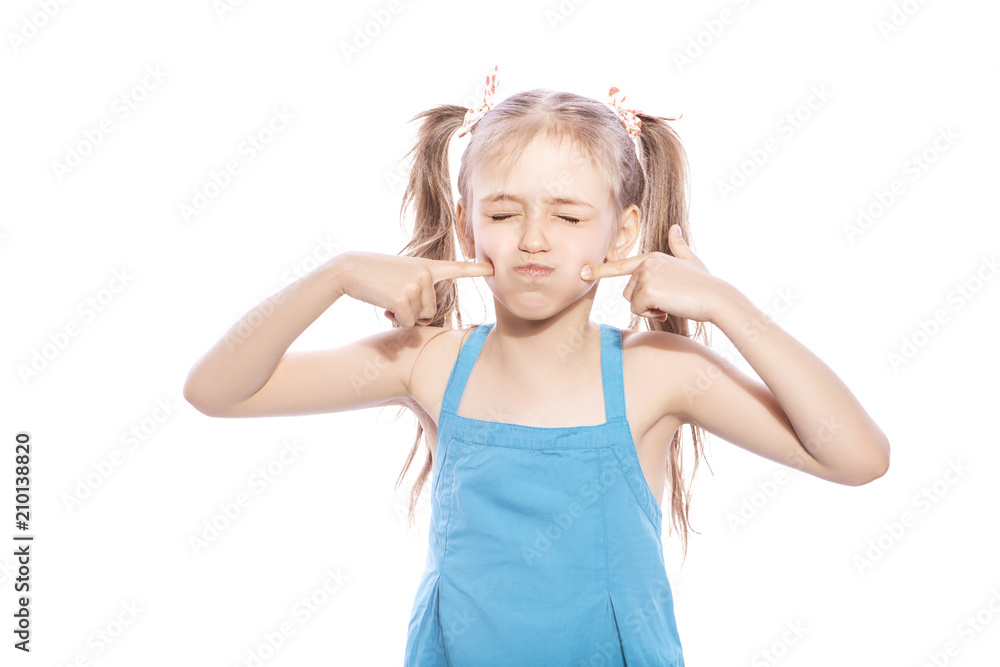 Young seven years old brunette girl in blue dress on a white isolated background. She blows her cheeks, funny emotions on her face Young seven years old brunette girl in blue dress on a white isolated background. She blows her cheeks, funny emotions on her face
