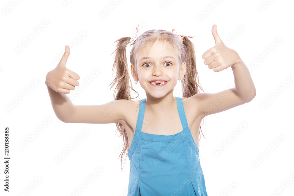 Young seven years old brunette girl in blue dress on a white isolated background. She make thumbs up gesture with her hands, smiling and happiness and joy emotions on her face Young seven years old brunette girl in blue dress on a white isolated background. She make thumbs up gesture with her hands, smiling and happiness and joy emotions on her face