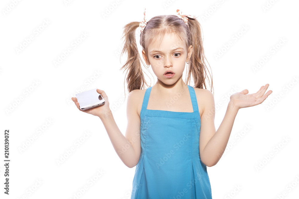 Young seven years old brunette girl in blue dress on a white isolated background. Amazement, surprise emotions on her face. Talking on the phone Young seven years old brunette girl in blue dress on a white isolated background. Amazement, surprise emotions on her face. Talking on the phone