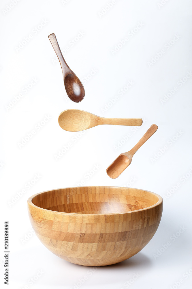 Wooden bowl spoon utensils on white background elevated flying floating Wooden bowl spoon utensils on white background elevated flying floating