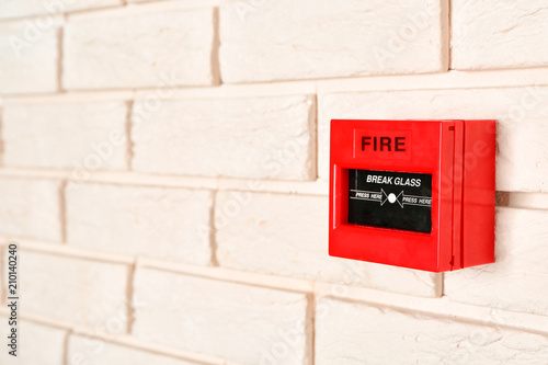 Modern fire call point on brick wall indoors