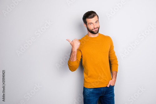 Portrait of cheerful attractive joyful confident guy keeping hand in pocket of jeans hinting pointing on copyspace behind his back isolated on gray background photo