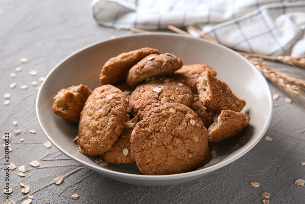 Bowl with delicious oatmeal cookies on textured background