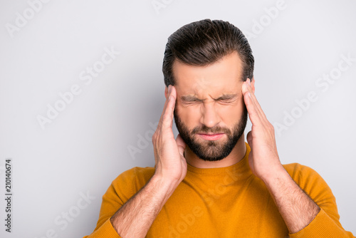 Close up portrait of unhealthy tired man touching his temples suffering from head ache isolated on gray background