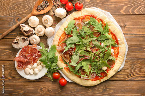 Raw pizza with tomato sauce and ingredients on table