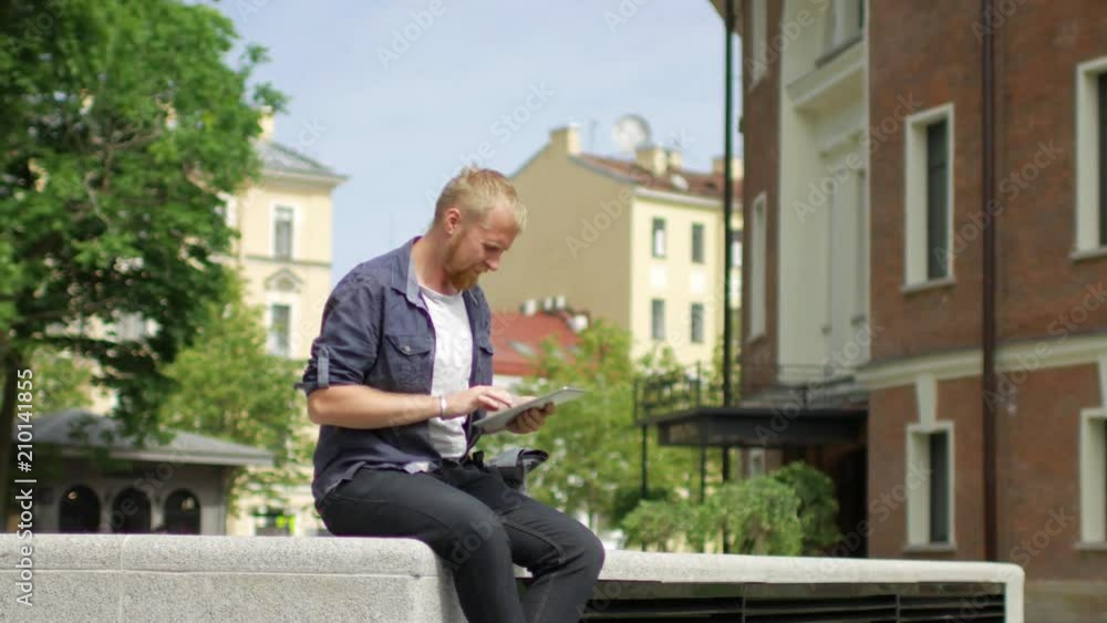 a man with a tablet sits on the street a man with a tablet sits on the street