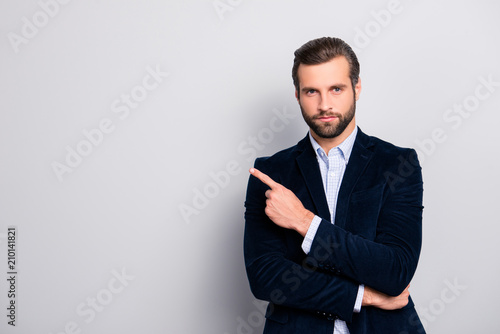 Portrait of handsome serious strict concentrated focused wealthy masculine virile elegant attractive banker with modern haircut pointing on empty blank space isolated on gray background copyspace