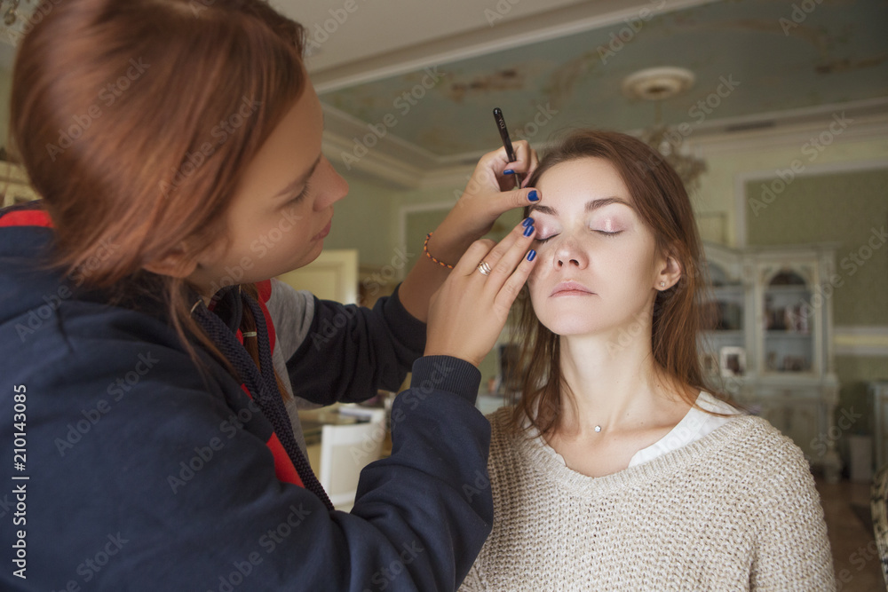 Brunette make up artist woman applying make up for a caucasian brunette bride, preparing her for a wedding photosession or a date Brunette make up artist woman applying make up for a caucasian brunette bride, preparing her for a wedding photosession or a date