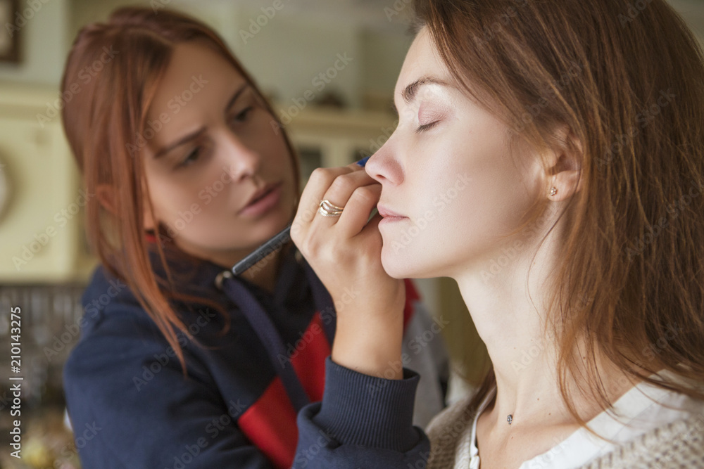 Brunette make up artist woman applying make up for a caucasian brunette bride, preparing her for a wedding photosession or a date Brunette make up artist woman applying make up for a caucasian brunette bride, preparing her for a wedding photosession or a date