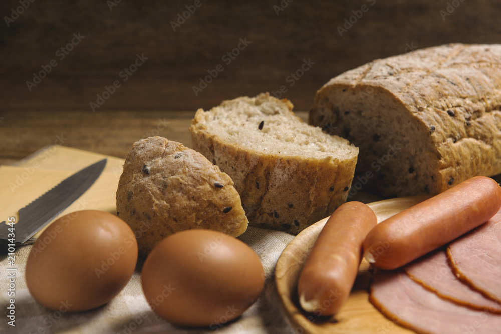 various ingredients for breakfast on wood background, bread, egg, sausage, ham, and cheese set on background various ingredients for breakfast on wood background, bread, egg, sausage, ham, and cheese set on background