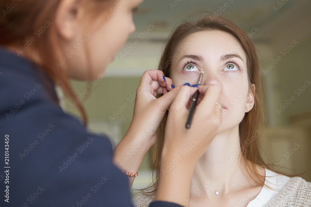 Brunette make up artist woman applying make up for a caucasian brunette bride, preparing her for a wedding photosession or a date Brunette make up artist woman applying make up for a caucasian brunette bride, preparing her for a wedding photosession or a date