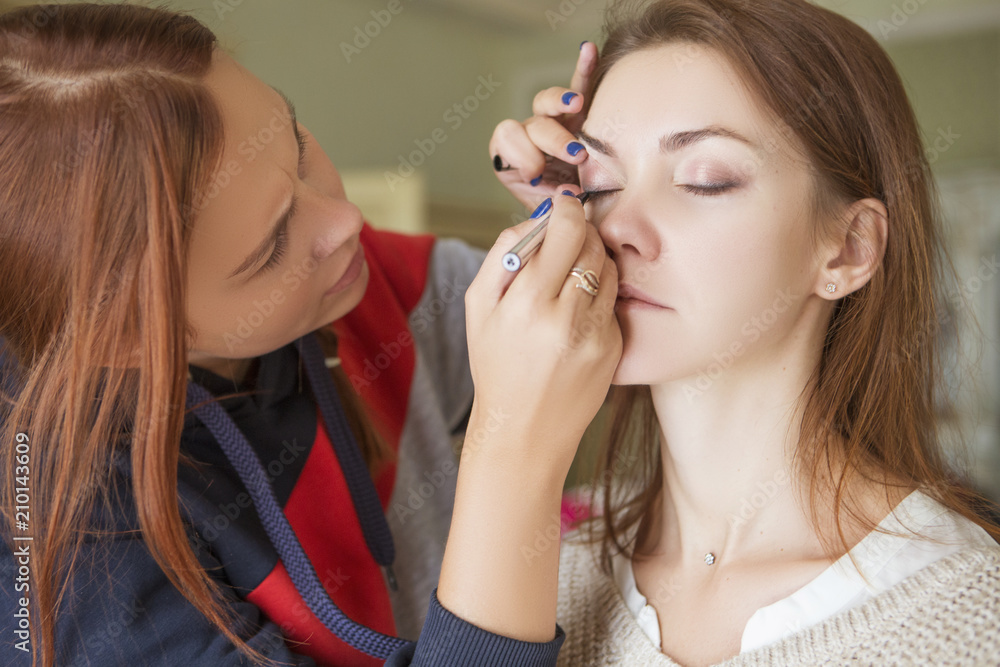 Brunette make up artist woman applying make up for a caucasian brunette bride, preparing her for a wedding photosession or a date Brunette make up artist woman applying make up for a caucasian brunette bride, preparing her for a wedding photosession or a date