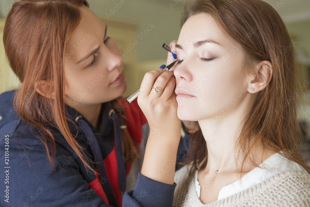 Brunette make up artist woman applying make up for a caucasian brunette bride, preparing her for a wedding photosession or a date Brunette make up artist woman applying make up for a caucasian brunette bride, preparing her for a wedding photosession or a date