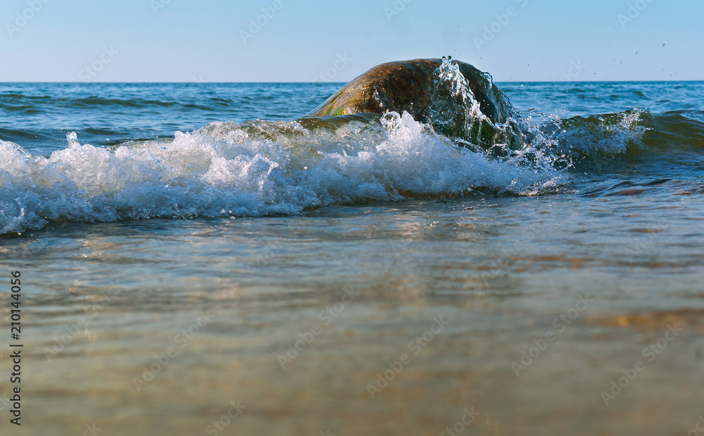 Obraz premium Rocks on the seashore. The sandy shore of the sea. Waves on the Baltic Sea.