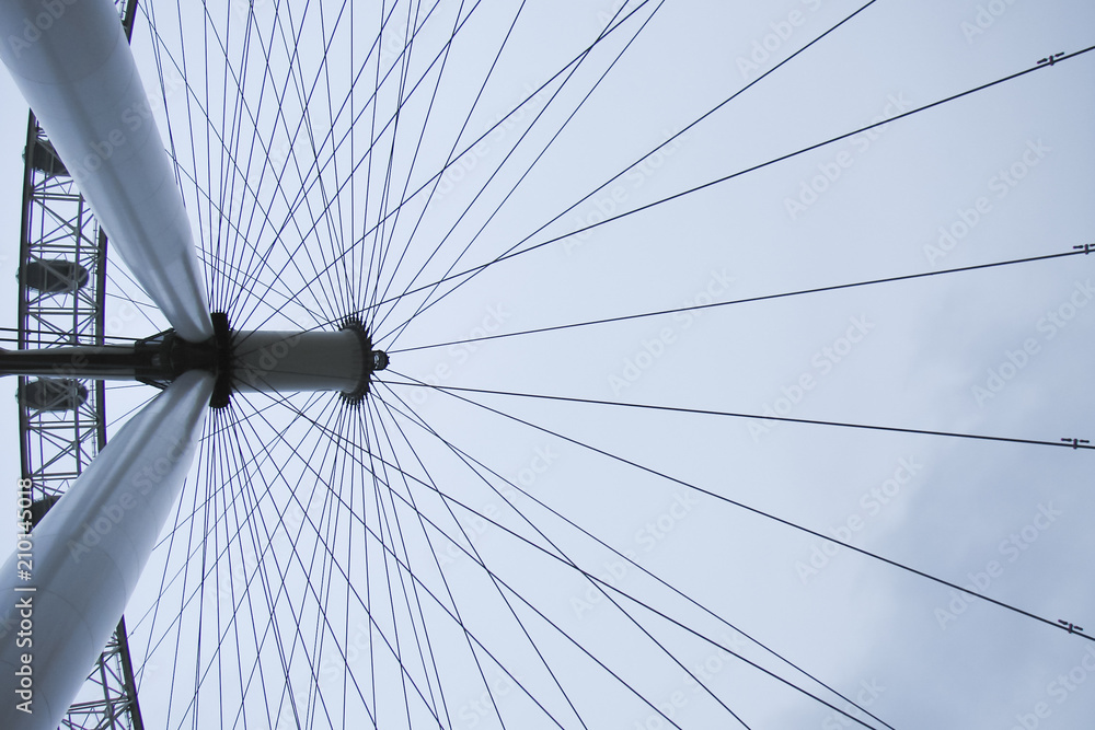 a giant wheel of the London Eye (UK), with a cloudy sky in the background; modern suspended structure