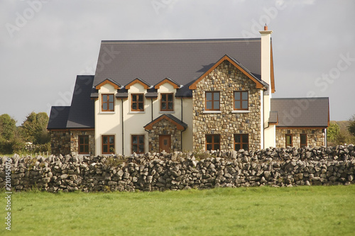 a solid stone rural house, separate entrances on all sides of the building; rough stone fence; Ireland