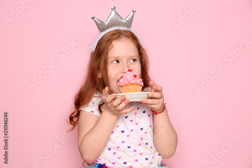 Schilderij op canvas Cute little girl eating birthday cupcake on color background