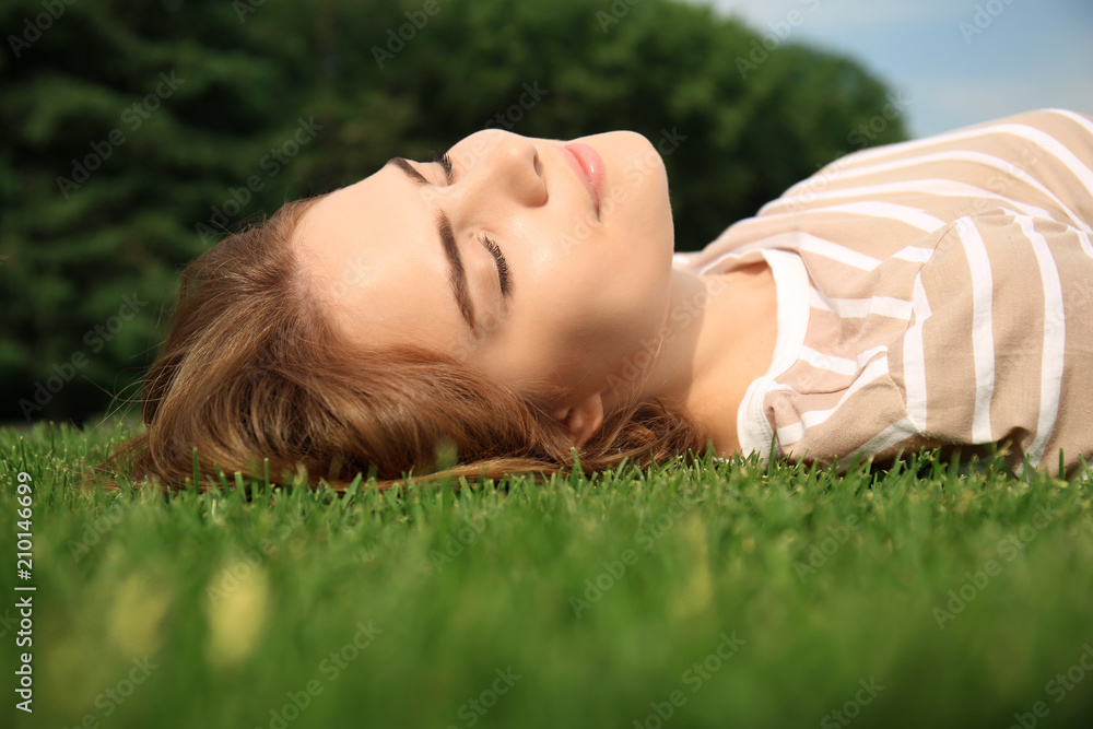 Young woman relaxing on green grass outdoors Young woman relaxing on green grass outdoors