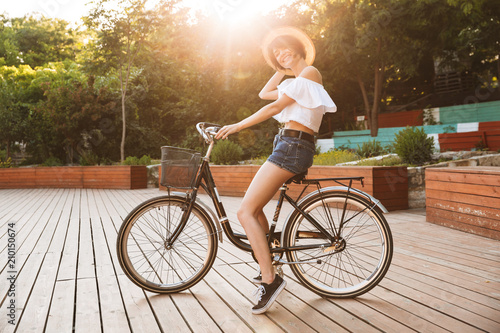 Smiling young girl in summer clothes riding bicycle