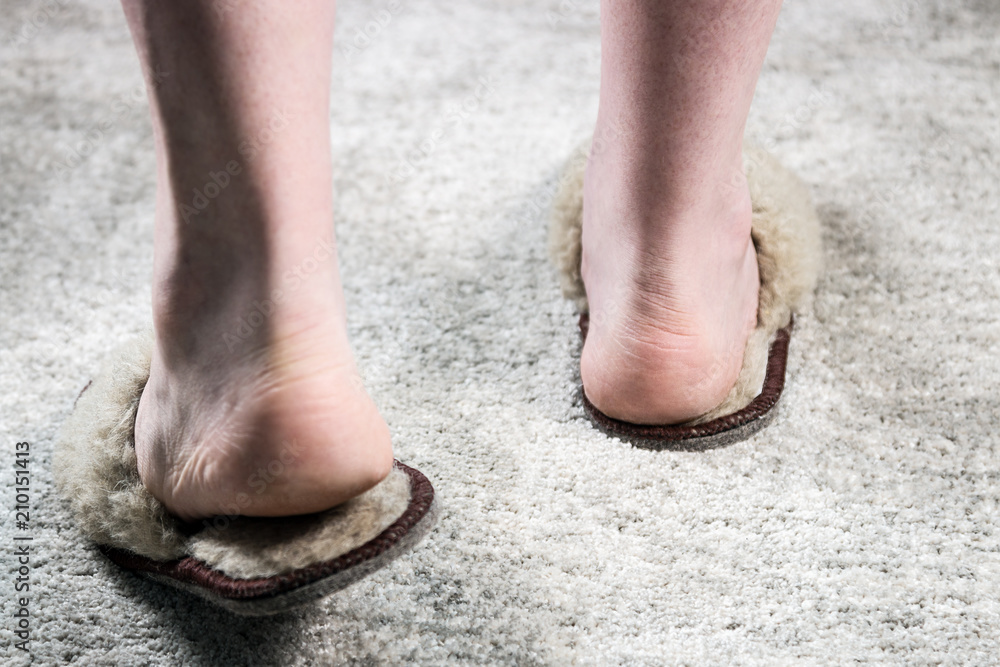 fluffy Slippers on feet on the carpet in the room fluffy Slippers on feet on the carpet in the room