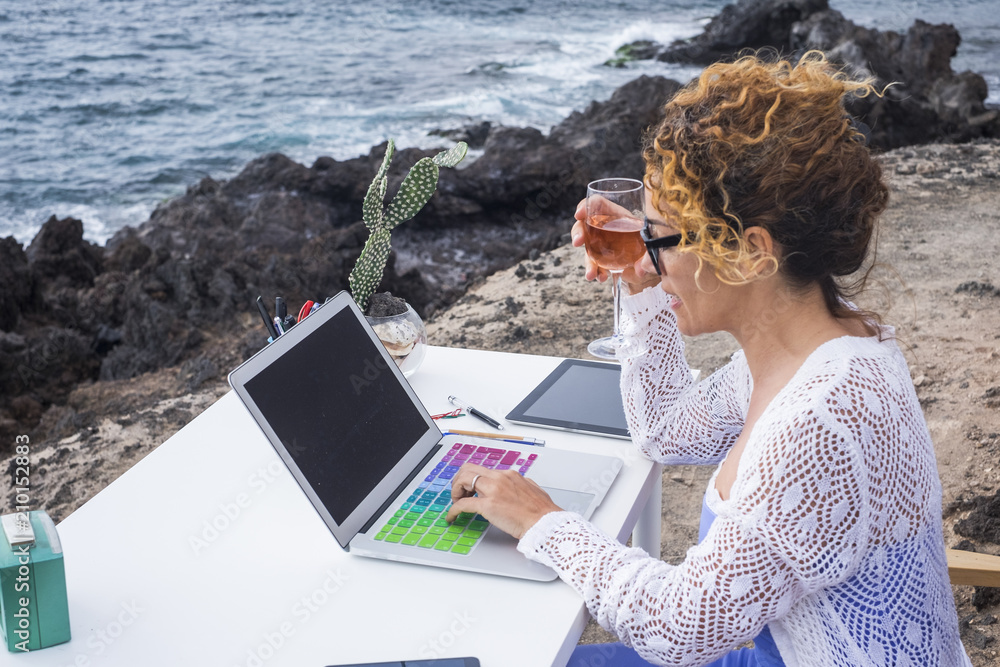 Alternative office outdoor near the ocean waves to work freedom with internet connections and far away teamworks or e-commerce shop. nice beautiful lady working happy with laptop outdoors