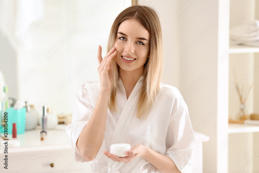 Beautiful young woman applying cream in morning Beautiful young woman applying cream in morning