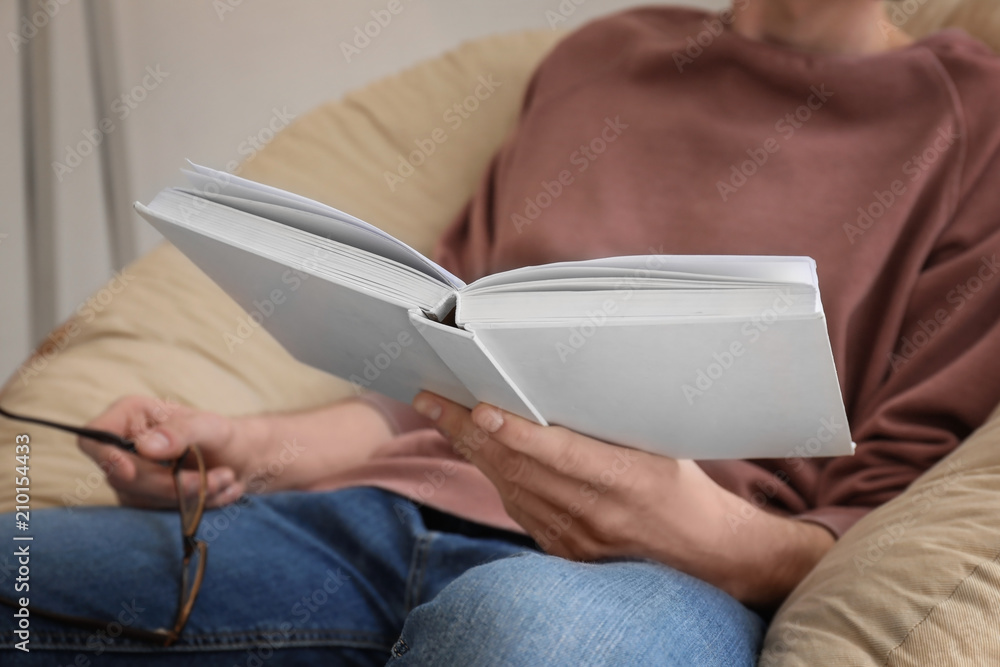 Obraz premium Young man reading book at home, closeup