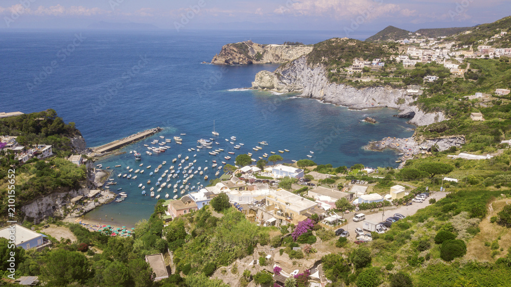 Aerial view of the beach and the small harbor of Cala Feola on the island of Ponza, in Italy. There are many boats and motorboats of tourists anchored in the bay and sheltered in the mountains.
