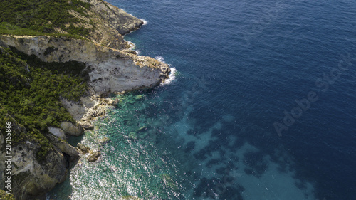 Aerial view of a rocky coastline overlooking the Mediterranean Sea. On the mountain grows a forest with many trees and there is some big rock in the blue and azure sea. © Stefano Tammaro