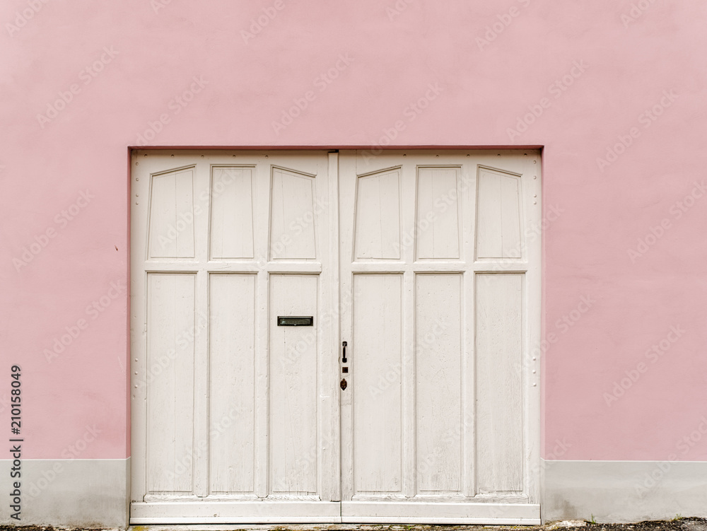White front door on pink colored house wall, Italy