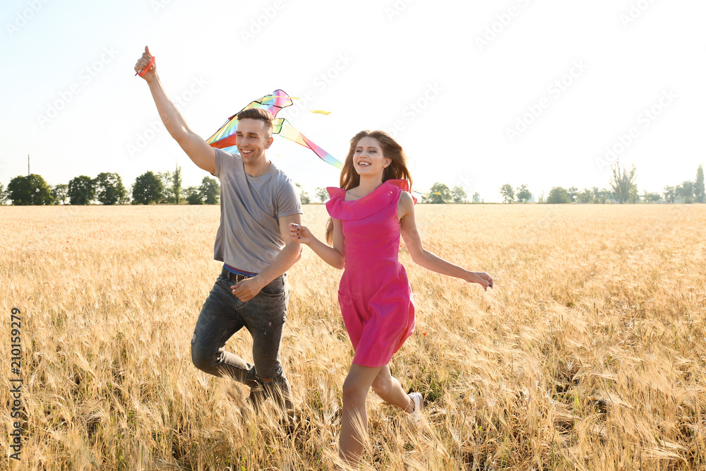 Happy young couple flying kite in a field Happy young couple flying kite in a field
