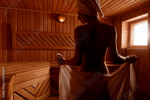 girl in a spa treatment in a traditional sauna with a brush for skin and a washcloth. relaxes wrapped in a white towel photo