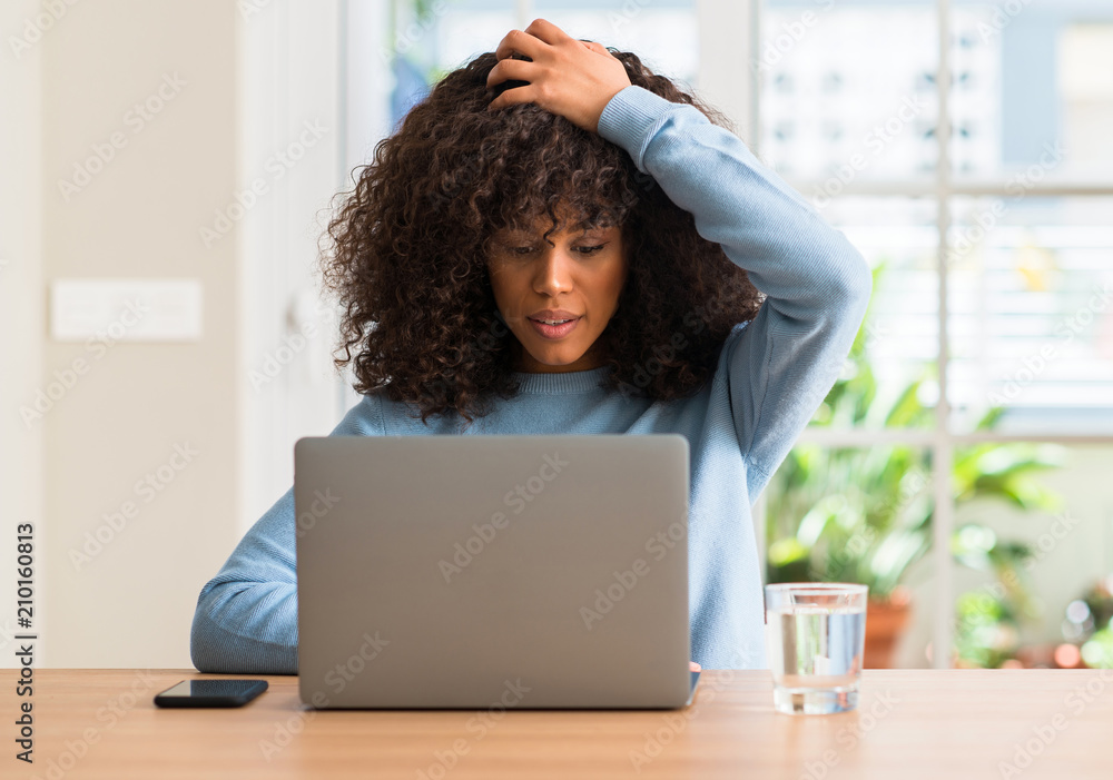 African american woman using laptop computer at home stressed with hand on head, shocked with shame and surprise face, angry and frustrated. Fear and upset for mistake. African american woman using laptop computer at home stressed with hand on head, shocked with shame and surprise face, angry and frustrated. Fear and upset for mistake.