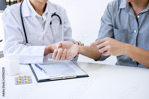 Doctor in white coat taking and checking the Patient s wrist pain during the examination