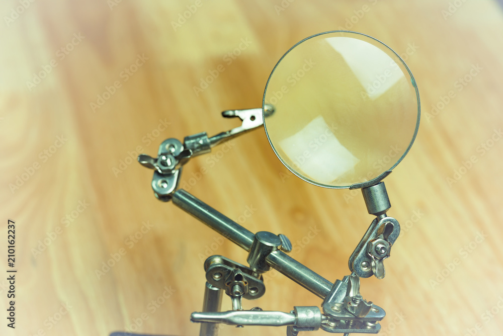 Glass magnifier on jig for holding small piece of electronics, repairing concept. Glass magnifier on jig for holding small piece of electronics, repairing concept.