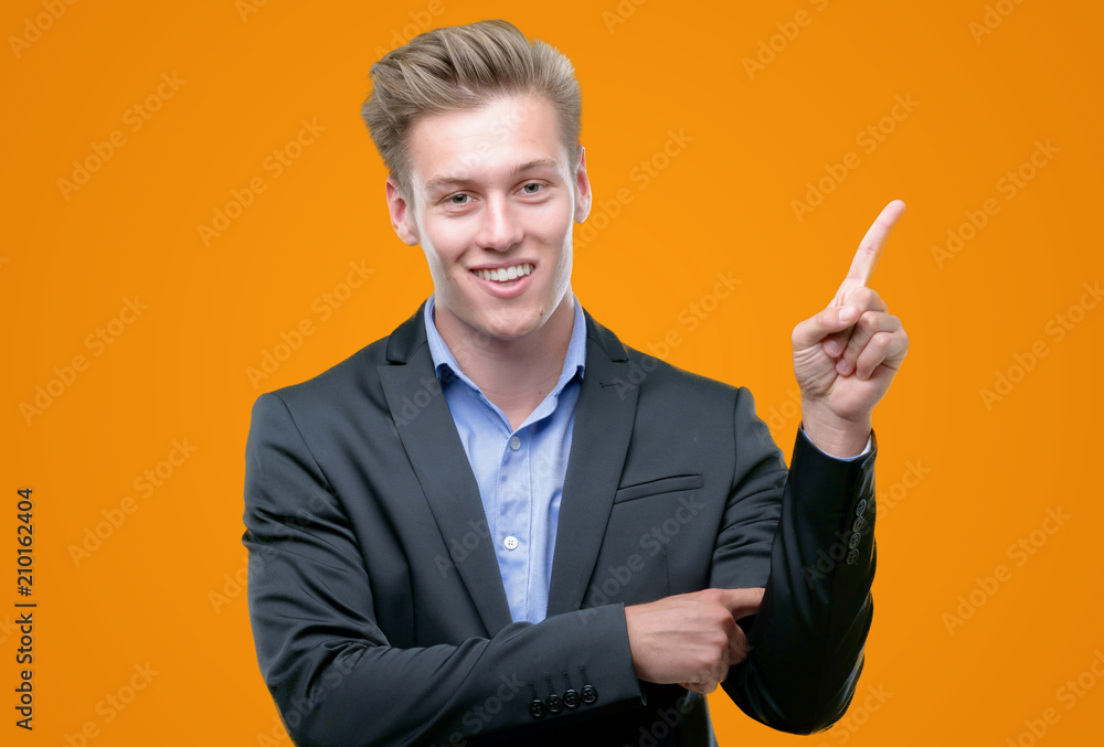 Young handsome blond business man very happy pointing with hand and finger to the side Young handsome blond business man very happy pointing with hand and finger to the side