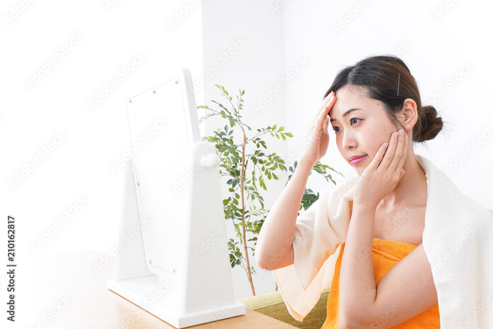 部屋でスキンケアをする若い女性
