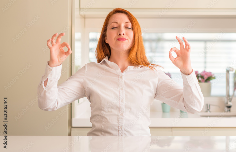 Redhead woman at kitchen relax and smiling with eyes closed doing meditation gesture with fingers. Yoga concept. Redhead woman at kitchen relax and smiling with eyes closed doing meditation gesture with fingers. Yoga concept.